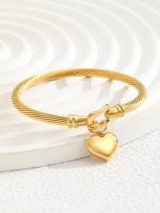 Detail of 18K gold-plated twisted cable cuff bracelet with a polished heart charm