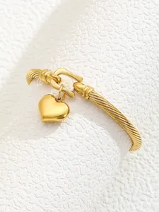 Detail of 18K gold plated stainless steel twisted cuff bangle with a heart charm