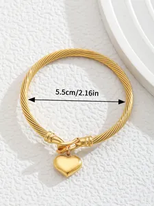 Detail of twisted 18K gold plated cuff with heart charm and 5.5cm inner diameter