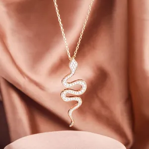 Elegante gouden slangenketting met fonkelende kristallen op een zijden achtergrond