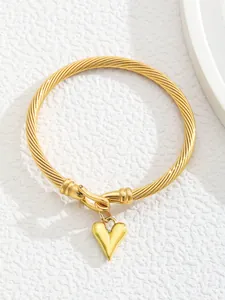 Detail of 18K gold plated spiral cuff bracelet featuring a polished heart pendant