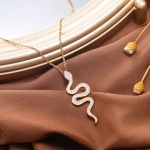 Detailweergave van gouden slangenhanger met witte zirkoon op zijden stoffen achtergrond