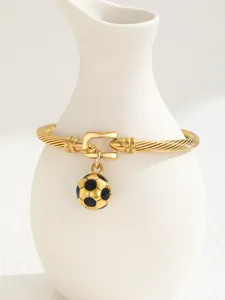 Detail of 18K gold-plated C-shaped cuff with a black enamel football charm and cable pattern