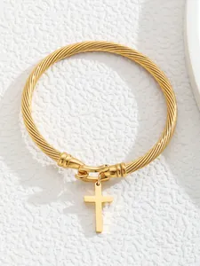Detail of 18K gold-plated twisted cable bracelet featuring a cross pendant on a white background