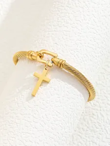 Macro detail of 18K gold plated twisted cable cuff bracelet with a polished cross charm