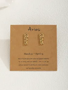 Détail de boucles d'oreilles signe Bélier dorées sur carte de présentation
