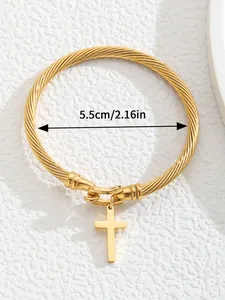 Macro detail of 18K gold-plated twisted cable cuff bracelet with a cross pendant charm
