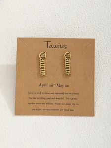 Boucles d'oreilles signe Taureau dorées présentées sur une carte en papier kraft