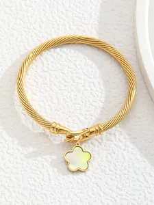 Detail of 18K gold stainless steel cable cuff bracelet with a green floral charm