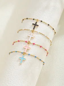 Vue détaillée de bracelets croix dorés avec perles en émail colorées et fini poli