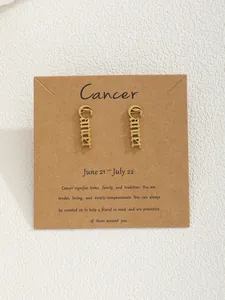 Gros plan de boucles d'oreilles signe Cancer dorées sur carte en papier kraft