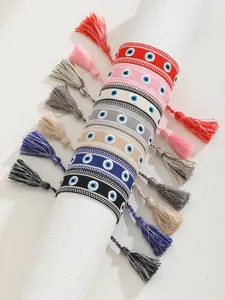 Detail of colorful braided Evil Eye bracelets with cotton tassels on white display stand