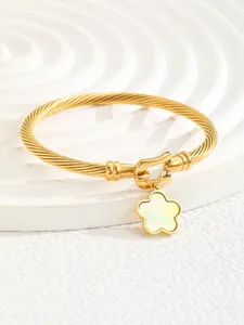 Macro view of 18K gold-plated twisted cuff with a white shell flower charm detail