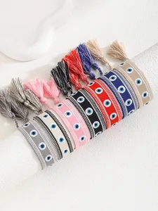 Detail of woven evil eye bracelets in various colors with tassels on a jewelry display stand