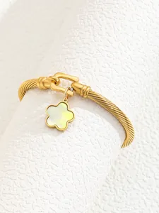Detail of 18K gold-plated twisted cable cuff bracelet with shell flower charm and U-clasp
