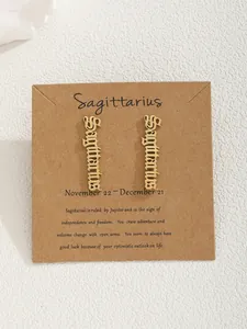Gros plan de boucles d'oreilles Sagittaire dorées sur carte kraft avec détails zodiac