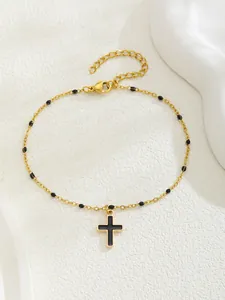 Détail du bracelet croix plaqué or avec perles noires et fermoir mousqueton réglable