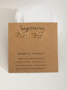 Dettaglio orecchini costellazione Sagittario in oro con zirconi su cartoncino