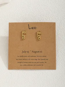 Détail des boucles d'oreilles Lion dorées sur support kraft avec description du signe