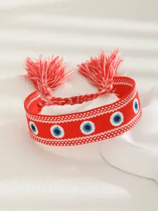 Detail of red woven Evil Eye bracelet with intricate embroidery and silk tassels