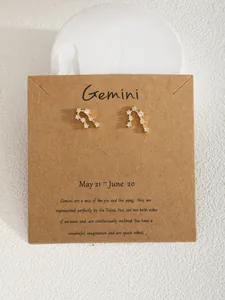 Dettaglio degli orecchini Gemini in oro con zirconi su cartoncino in carta kraft