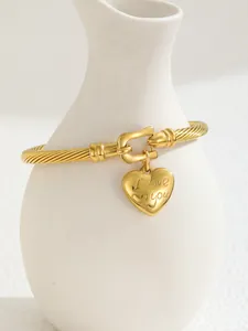 Macro shot of 18K gold plated cable bracelet with engraved heart charm and horseshoe clasp