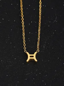 Gros plan du collier doré signe gémeaux sur un fond de ciel étoilé scintillant