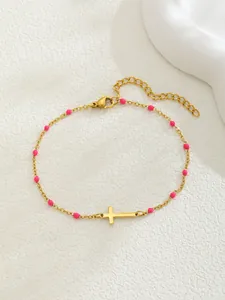 Détail du bracelet croix dorée avec perles roses et fermoir mousqueton réglable