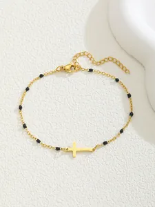 Vue détaillée du bracelet en chaîne dorée avec perles noires et breloque croix sur pierre