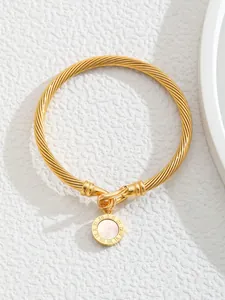 Close-up of 18K gold-plated C-shaped cuff featuring a Roman numeral mother of pearl charm
