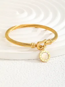 Detailed macro view of gold-plated twisted cable cuff with Roman numeral charm