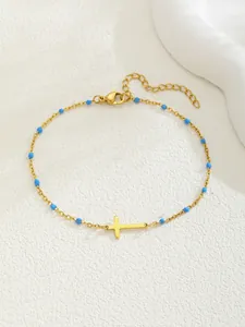 Détail du bracelet croix doré avec perles bleues montrant le fermoir et l'extension