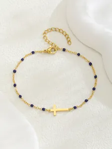 Détail du bracelet chaîne en or avec perles bleues et pendentif croix poli brillant