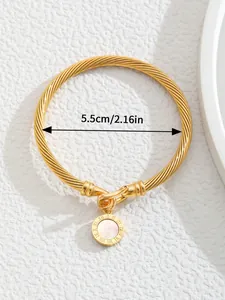 Macro detail of 18K gold plated C-shaped open bangle with coin shell pendant