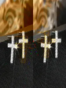 Detailaufnahme von Kreuz-Ohrsteckern in Gold und Silber mit funkelnden Zirkonia-Steinen