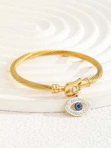 Detailed close-up of 18K gold-plated twisted cable cuff featuring a blue evil eye charm