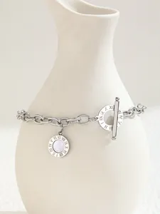 Detail of silver chain bracelet with Roman numerals and mother of pearl on ceramic vase