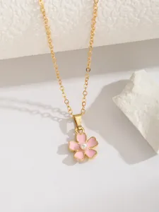 Détail d'un collier avec pendentif fleur rose, perle centrale et chaîne dorée fine