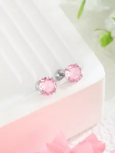 Dettaglio di orecchini con zirconi rosa e chiusura a vite argentata su supporto elegante