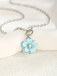 Detail of light blue enamel five-petal flower pendant with crystal center on silver chain