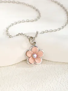Macro detail of silver necklace featuring a pink flower pendant with a sparkling center stone