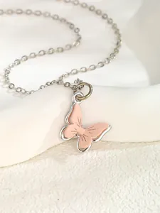 Macro detail of sweet pink butterfly pendant with delicate texture on a silver chain