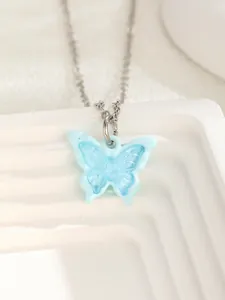 Macro shot of a light blue translucent resin butterfly pendant with a silver metal chain