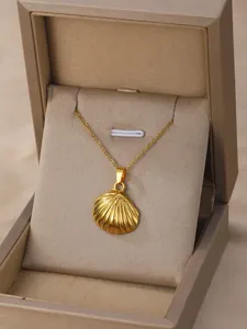 Close-up of golden shell pendant necklace with radial texture in a velvet jewelry box