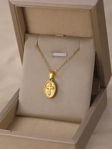 Detailed close-up of a golden oval pendant with an embossed cross in a jewelry box