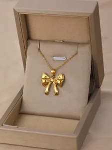 Close-up of golden bow-tie pendant necklace displayed in a beige jewelry gift box