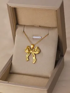 Close-up of golden bow pendant necklace displayed in a premium champagne gift box