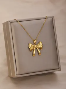 Close-up of golden bow pendant necklace with mirror finish on premium jewelry box