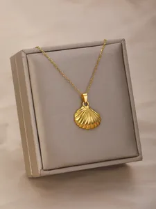 Close-up of a gold shell pendant necklace displayed on a premium grey jewelry box