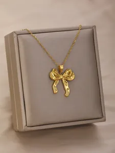 Detail of elegant gold-toned bow necklace displayed on a luxury grey jewelry box